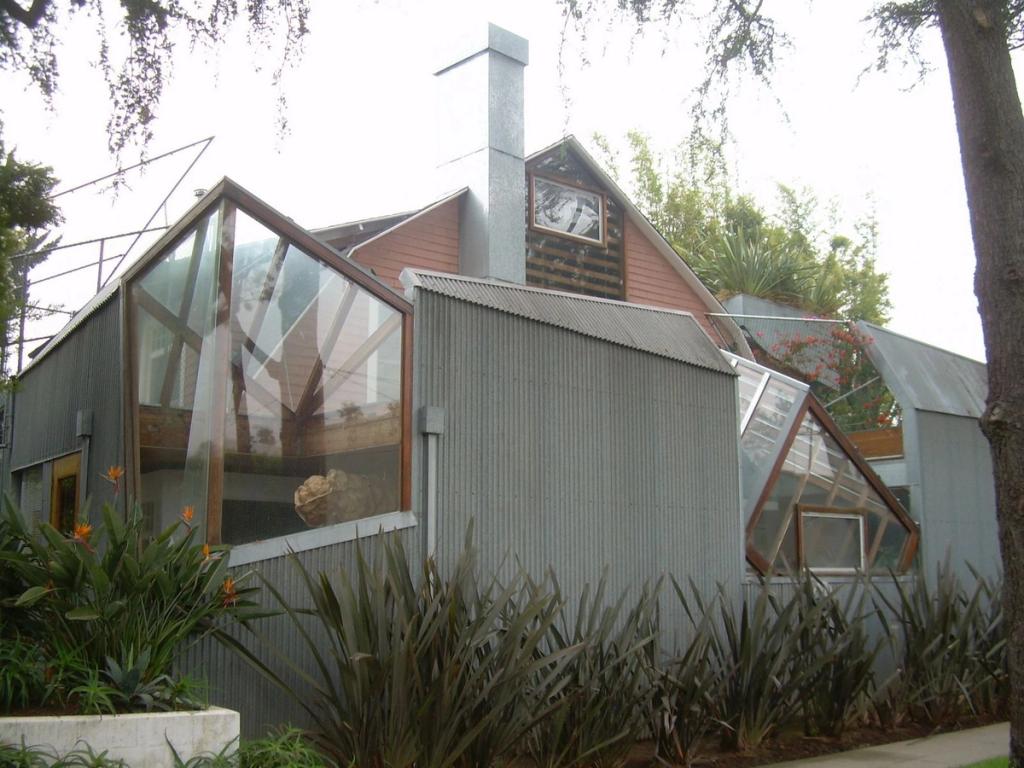 The façade of Gehry's house in corrugated sheet metal, with chamfered glazed projections above the pink house