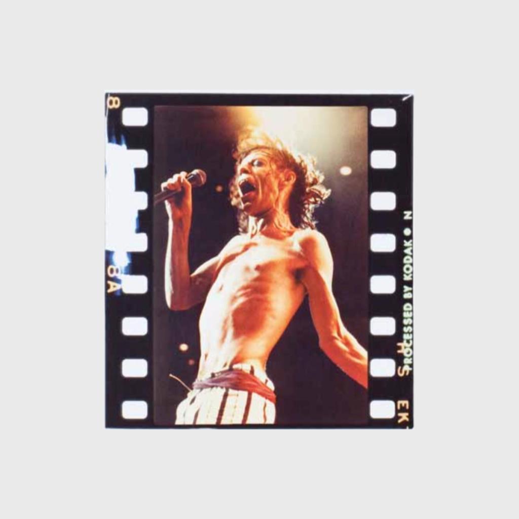 A colour film frame showing a shirtless Mick Jagger singing into a microphone