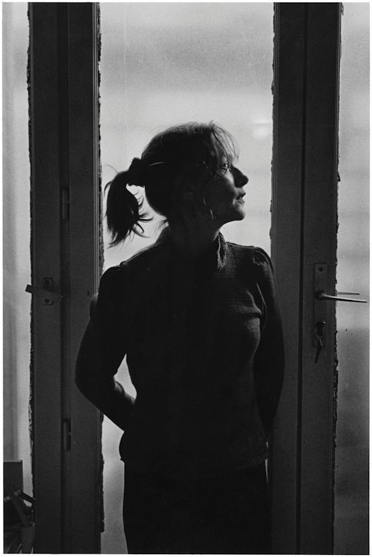 The silhouette of a woman with a ponytail standing in a doorway against the light