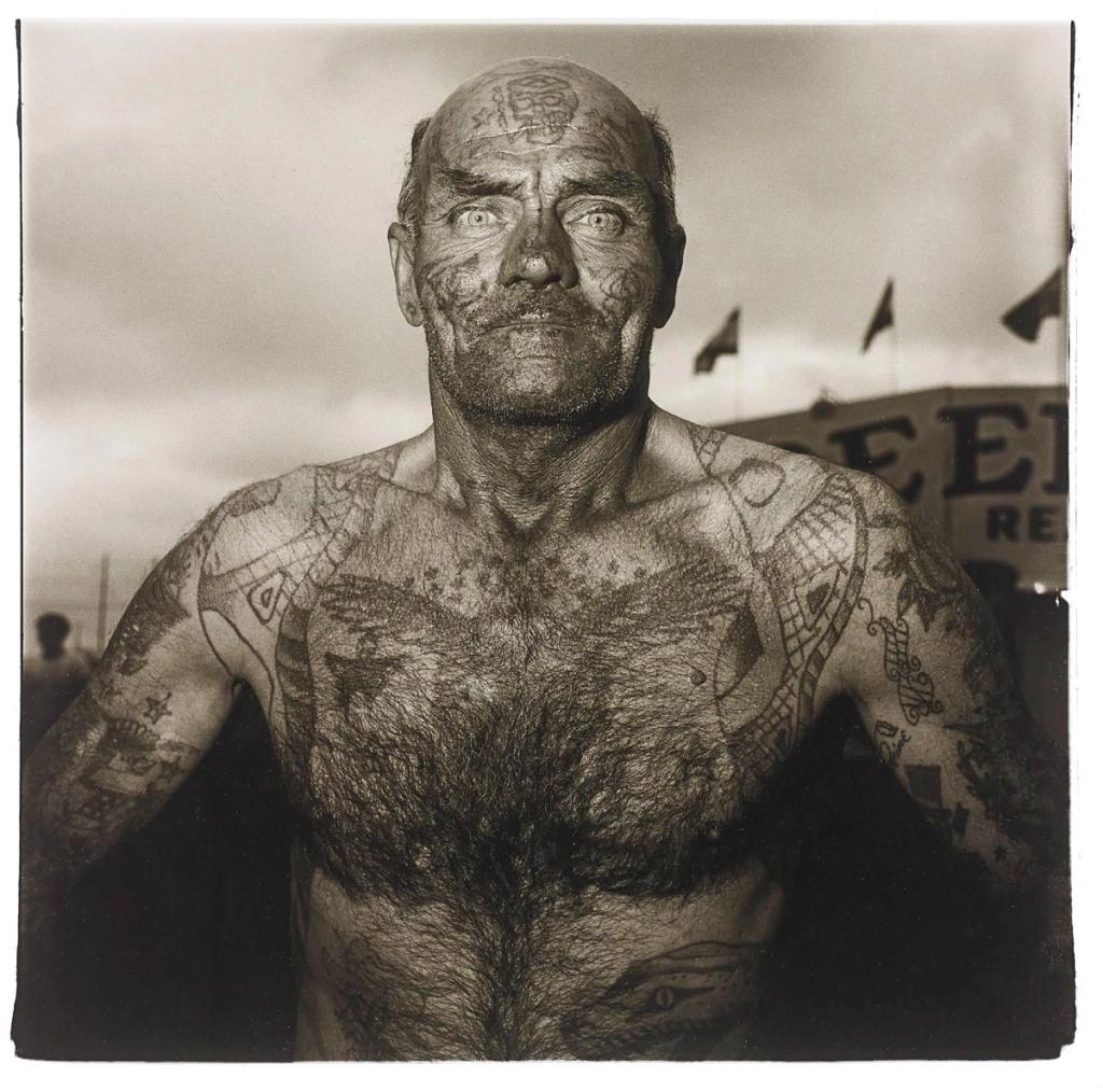 A bald man with tattoos covering his entire body and face, portrait by Diane Arbus