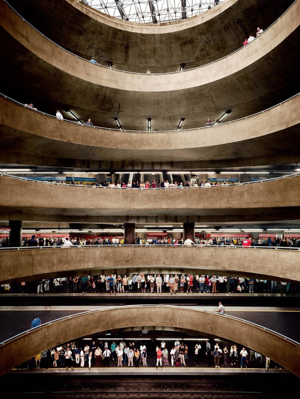 Tiered concrete platforms of an underground station, with crowds of passengers on every level