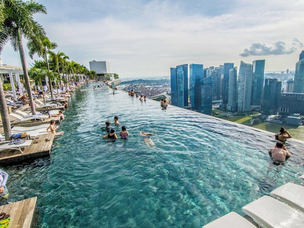Купающиеся в бассейне на крыше Marina Bay Sands с видом на деловой центр Сингапура