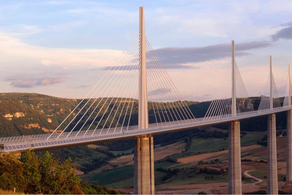 The tall piers and stay cables of the Millau Viaduct above the valley at sunset