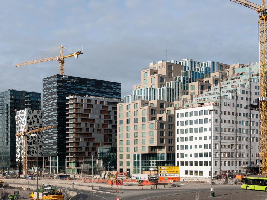 A row of towers with varied textures in Oslo's Barcode district, with a road and construction site in the foreground