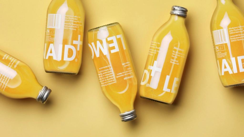 Жёлтые бутылки Lemonaid с белыми буквами лежат на жёлтом фоне