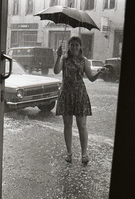 Two schoolchildren shield their heads with their satchels from the rain on a wet street, seen from above