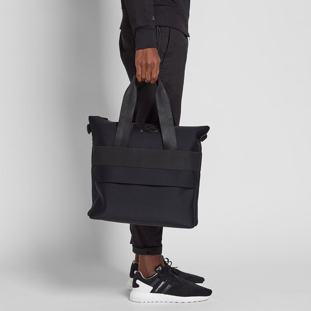 A Y-3 backpack with a multicolour pattern and logo on the back of a person dressed in black