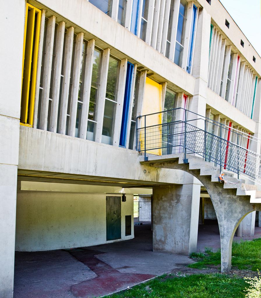 A concrete residential block with coloured window reveals and an exterior staircase