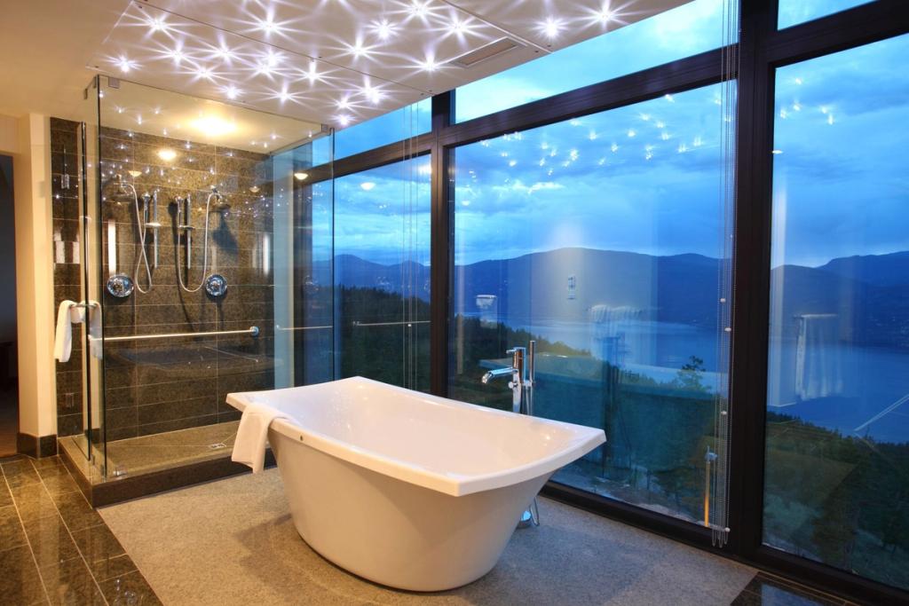 A bathroom with a freestanding bathtub and panoramic window overlooking Okanagan Lake