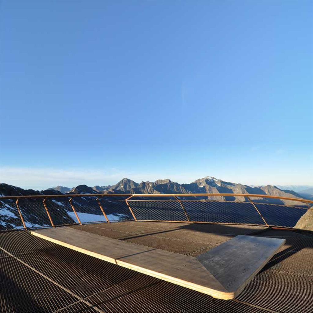The grid-pattern decking and railings of the Top of Tyrol platform with a panorama of Alpine peaks