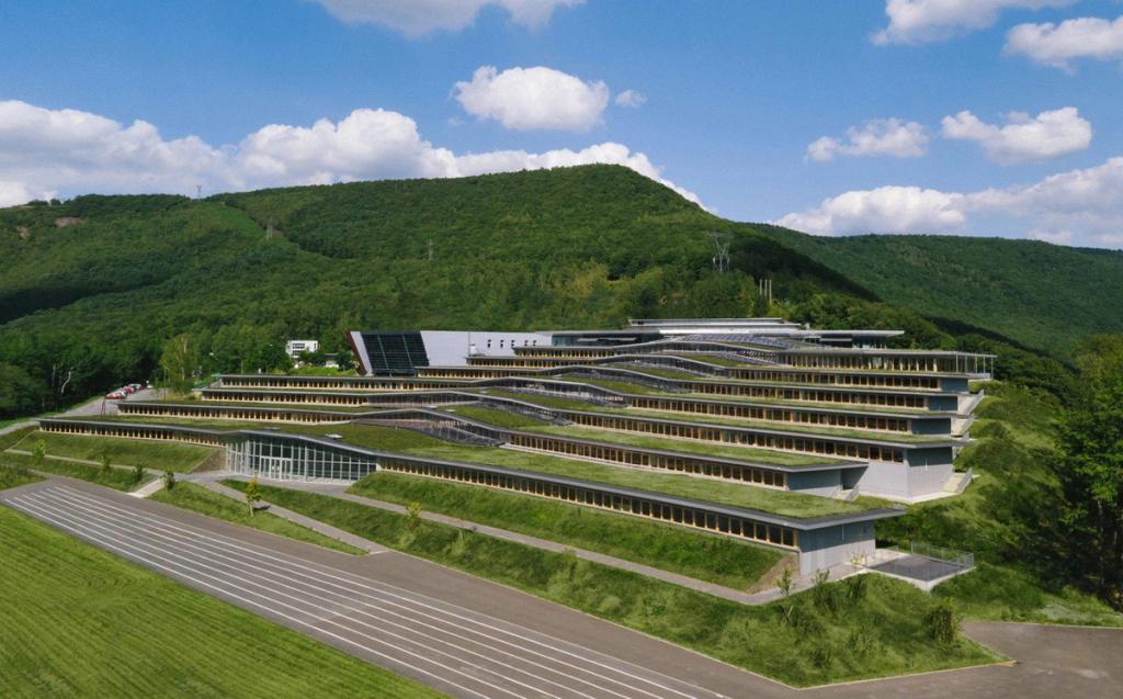 Jean Moulin School: a cascade of green-roofed terraces on a verdant hill beneath a cloudy sky