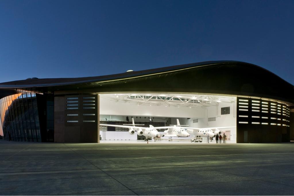 Spaceport America with its curved roof and aircraft inside the illuminated hangar at dusk