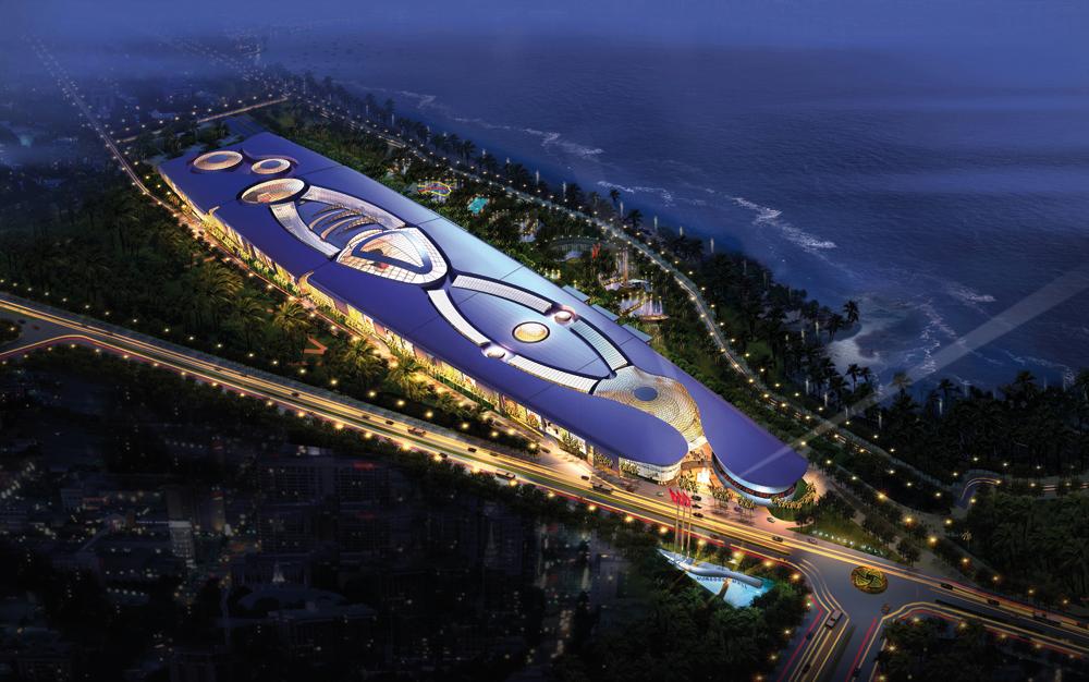 The elongated Morocco Mall building by the ocean in Casablanca at night, lit up