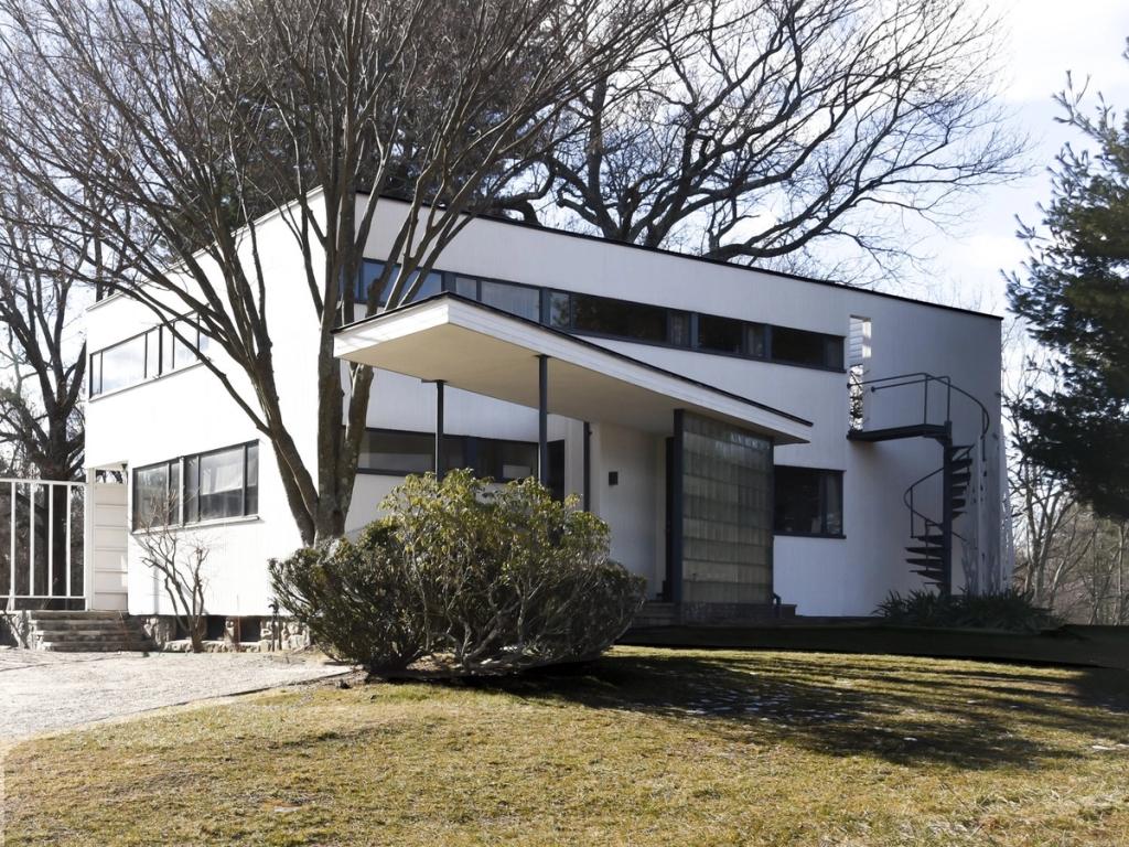 Gropius House in Lincoln, white-painted, with a canopy over the entrance and an external spiral staircase to one side, bare trees in the foreground