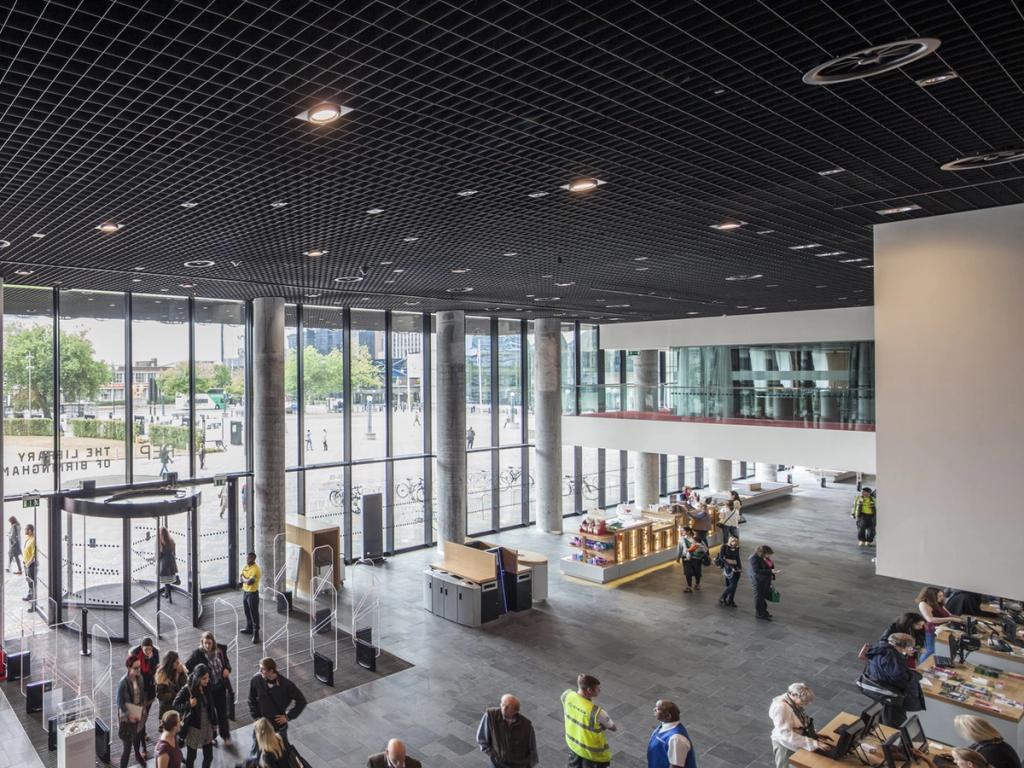 The spacious ground floor of the Library of Birmingham, featuring a glass wall, concrete columns and visitors