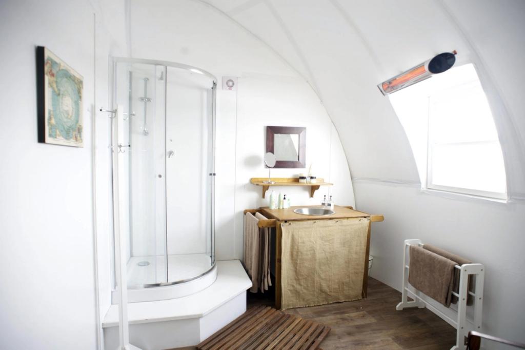A white bathroom inside a dome, with a shower cubicle and a washbasin