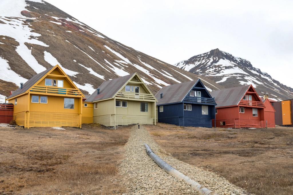 A row of colourful wooden houses in Longyearbyen at the foot of a mountain with patches of snow