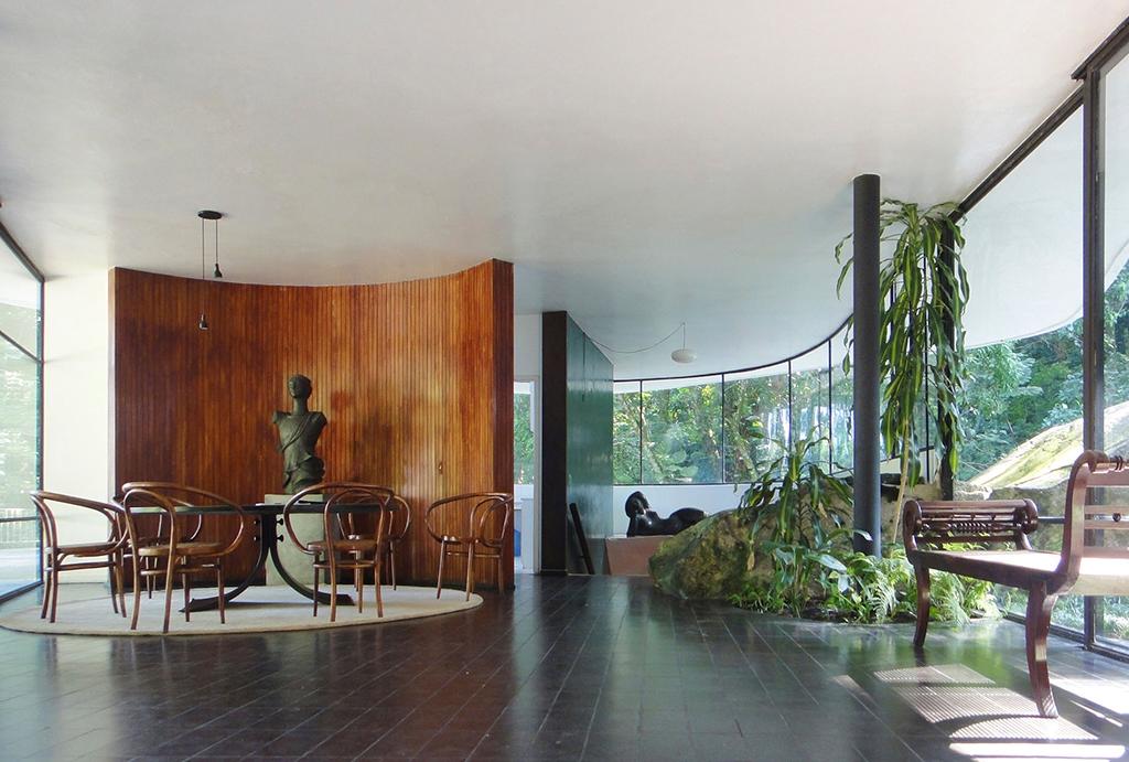 Interior of Casa Canoas with a curved timber wall and sculpture beside the glass walls