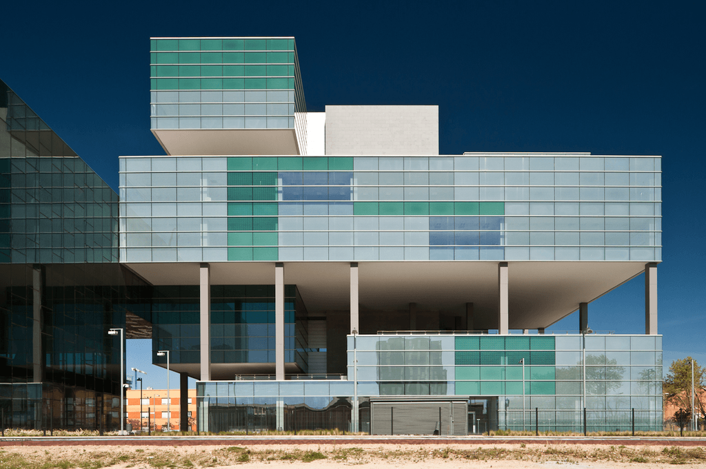The D38 office building, its glass facade rendered in shades of green and blue, raised on slender columns
