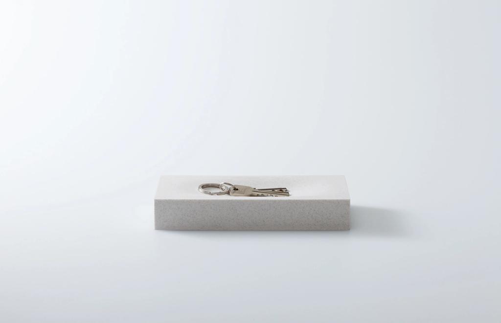A stone key tray with a set of keys on a white background
