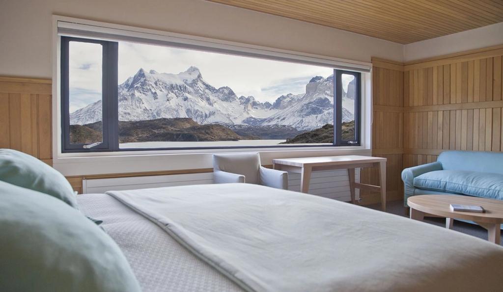 A room at Explora Patagonia with a panoramic window looking out onto the snow-capped peaks of Patagonia