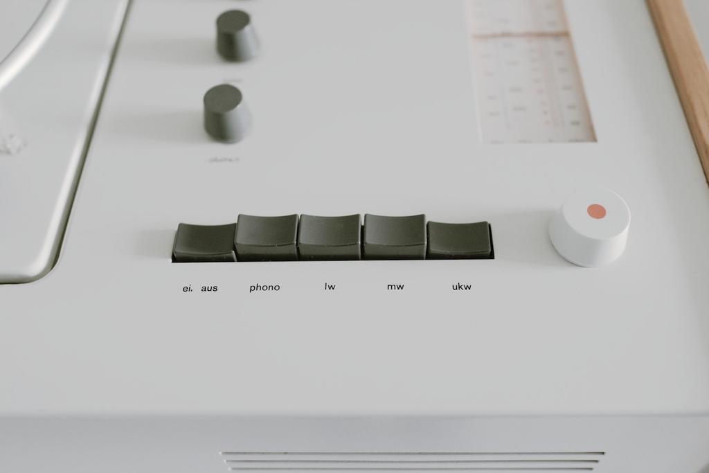 A hand turns a white round knob on the turntable's control panel