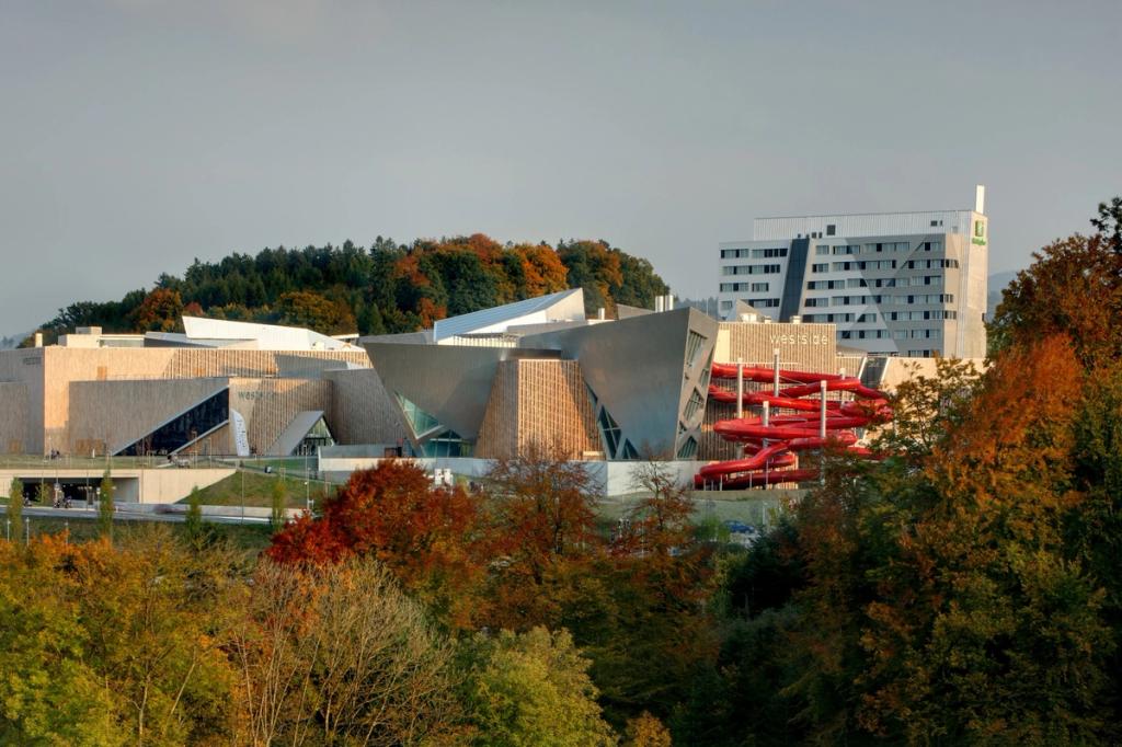 The Westside shopping centre in Bern set against an autumnal forest, with a red water slide