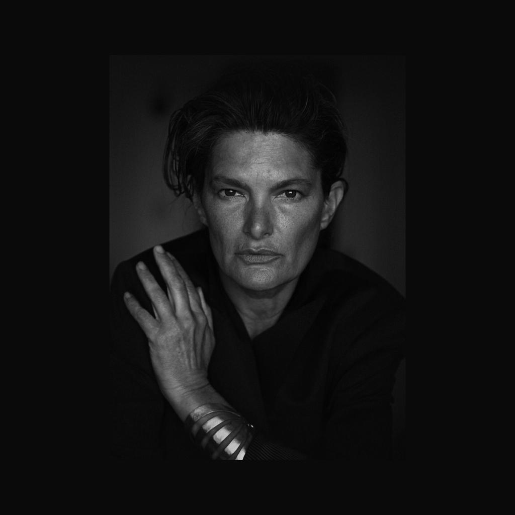 A black-and-white portrait of a woman in black clothing with a silver bracelet