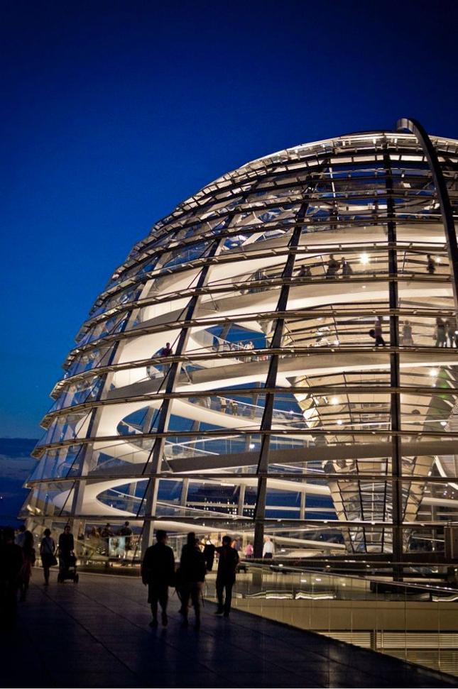 The illuminated glass dome of the Reichstag with its spiral ramps, photographed in the evening
