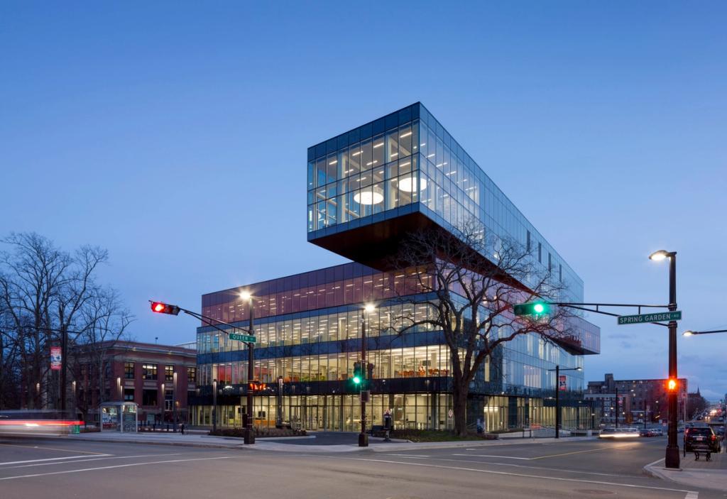 The glass Halifax library building with a projecting upper volume on a street corner in the evening