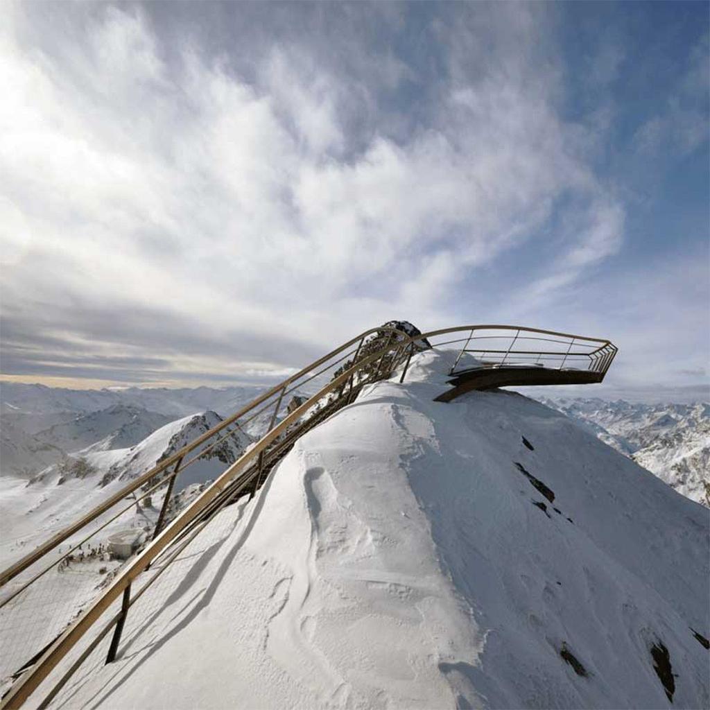 The Top of Tyrol viewing platform on a snow-covered mountain ridge in winter, surrounded by clouds