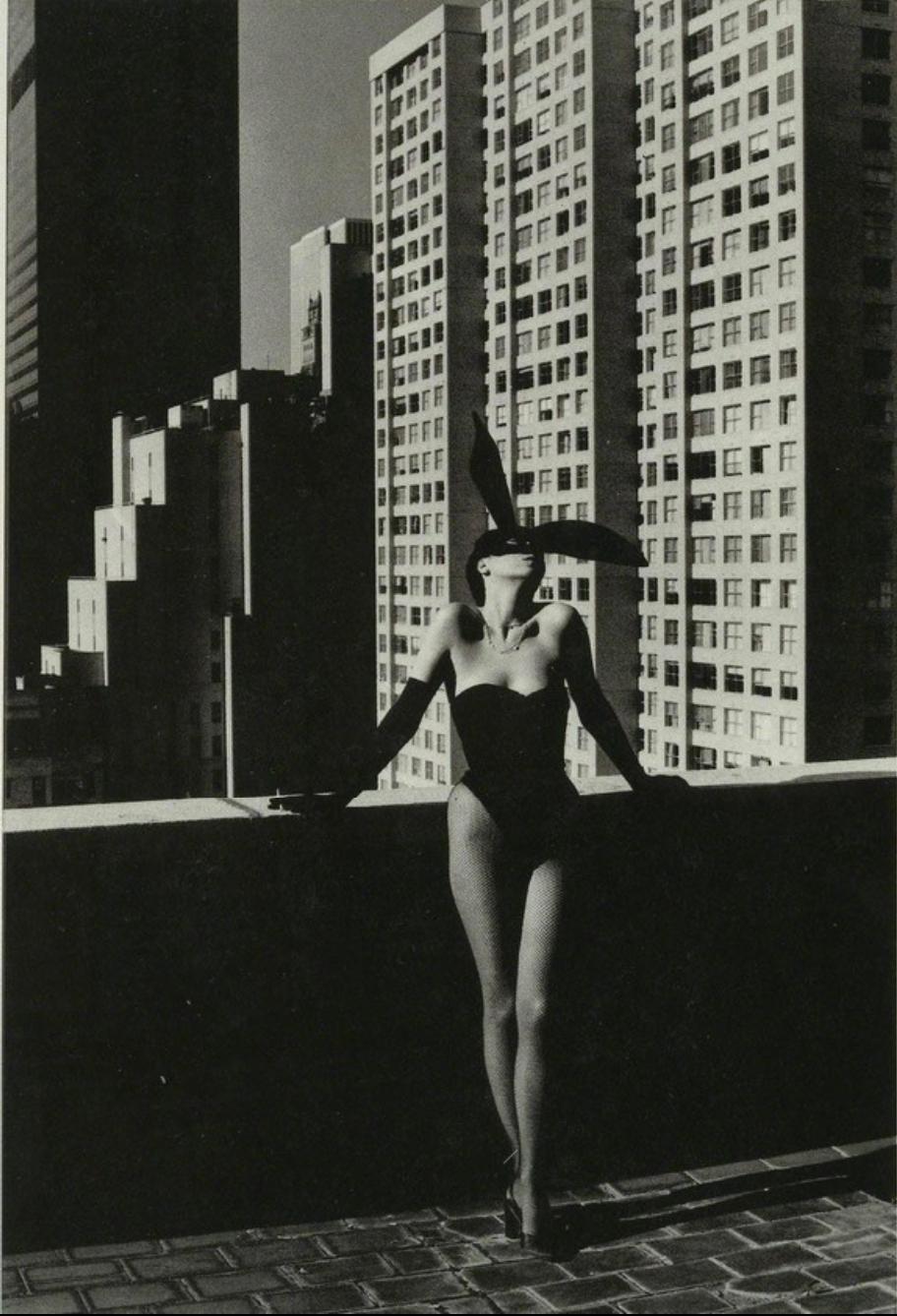 A woman in a black corset and a mask with rabbit ears against the backdrop of New York skyscrapers