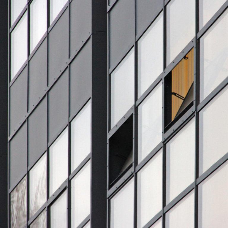 Detail of the Fagus Factory's glass facade, showing slender dark mullions and an open transom window