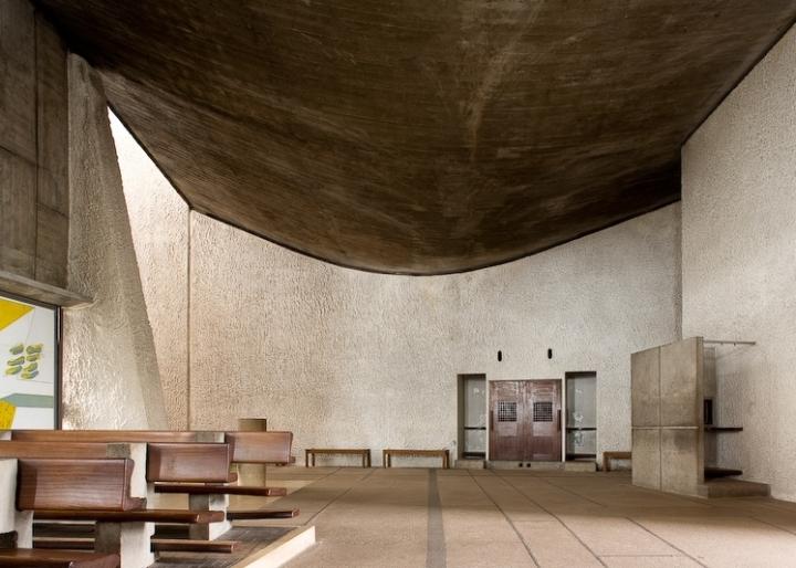 The interior of the Chapelle Notre-Dame-du-Haut with a dark curved ceiling and rough walls