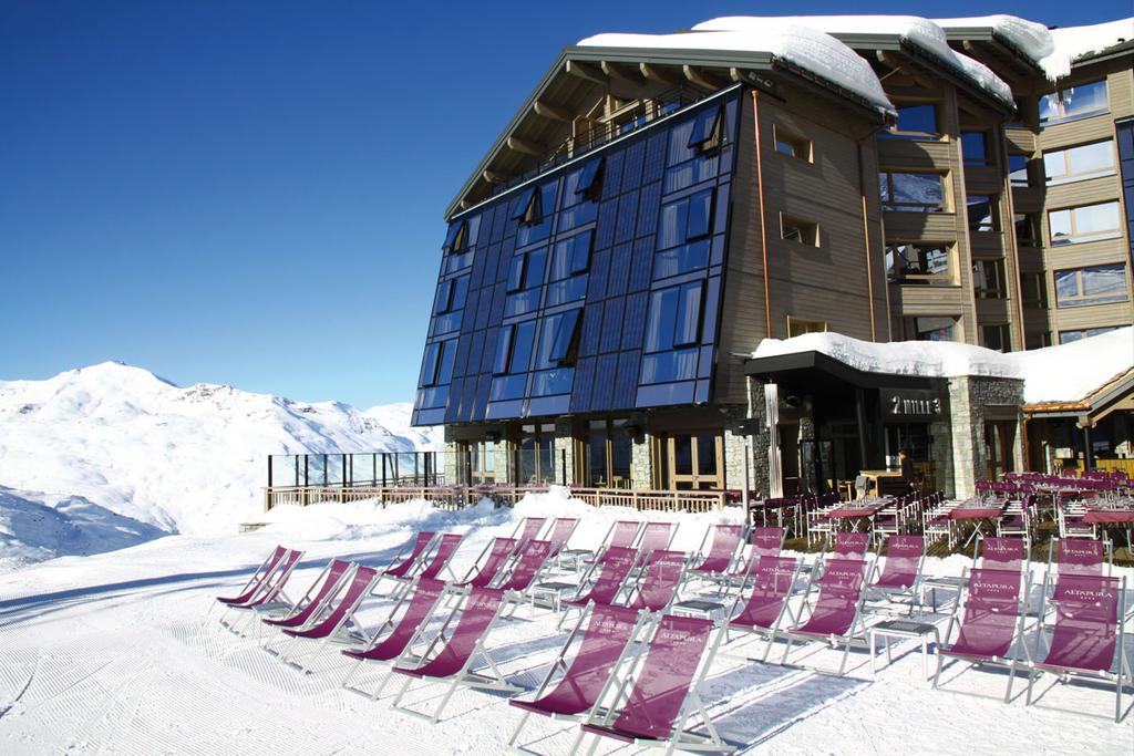 The Altapura façade with solar panels and sun loungers in the snow beside the ski run