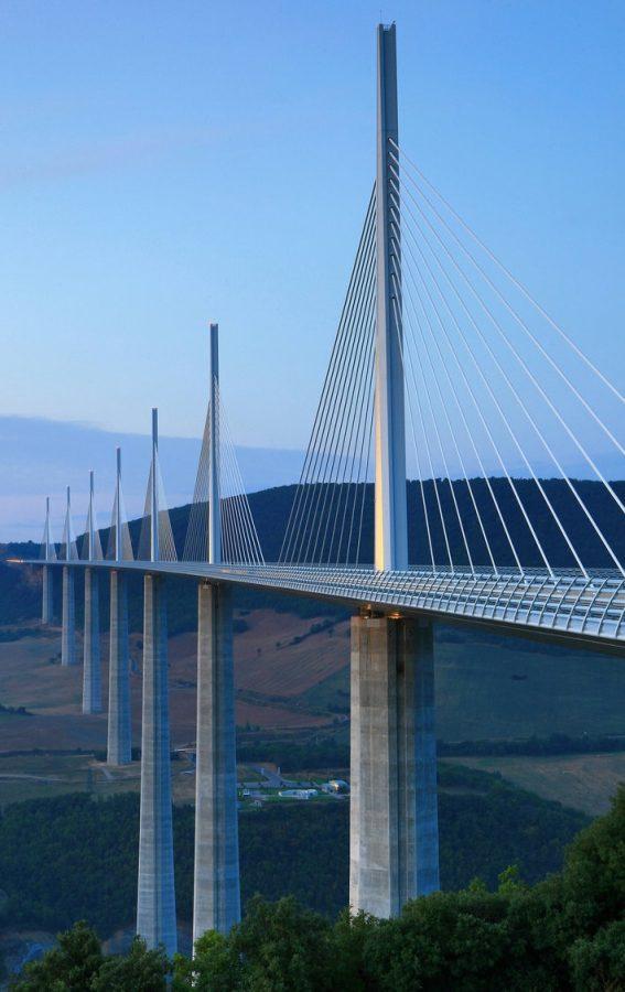 A tall concrete pier of the Millau Viaduct, splitting into a V-shape beneath the deck, with a cable-stay pylon