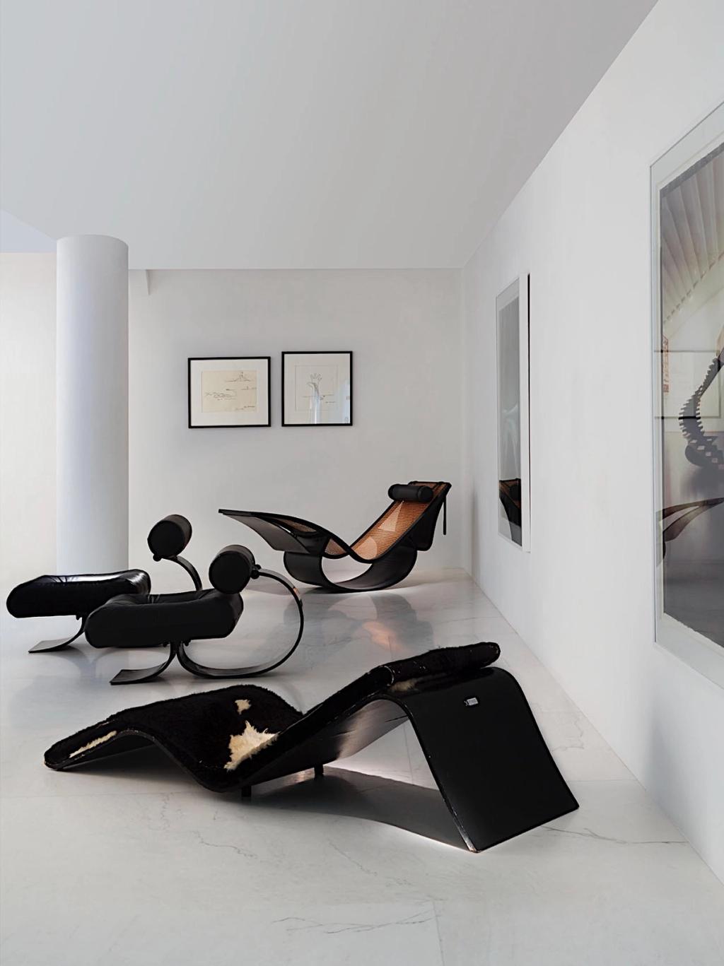 Black Niemeyer chaise longues in a white interior with drawings on the wall