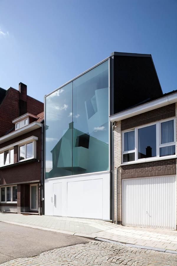 Дневной вид дома Narrow House, зеленоватое стекло фасада отражает небо, рядом традиционные кирпичные дома