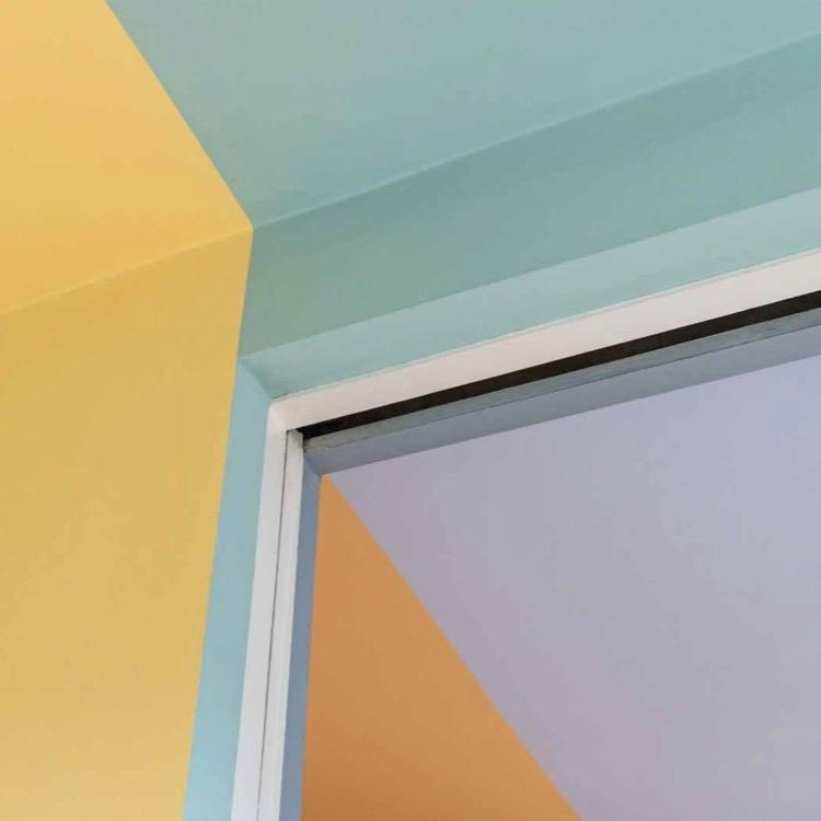 Corner of a doorway in Auerbach House with contrasting yellow, blue and lilac surfaces