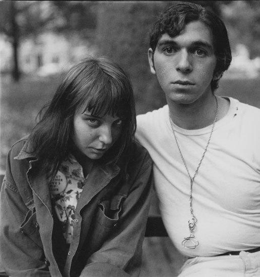 A close-up portrait of a young hippie couple on a park bench