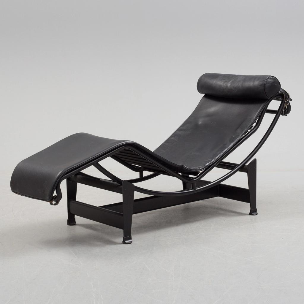 Charlotte Perriand's LC4 chaise longue in black leather on a steel frame with a cylindrical headrest