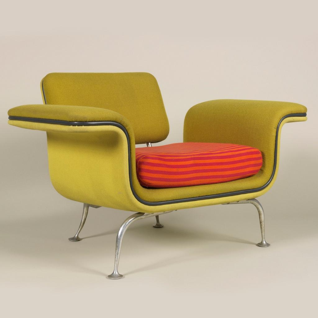 An Alexander Girard armchair with yellow upholstery, a red-and-orange striped cushion and metal legs