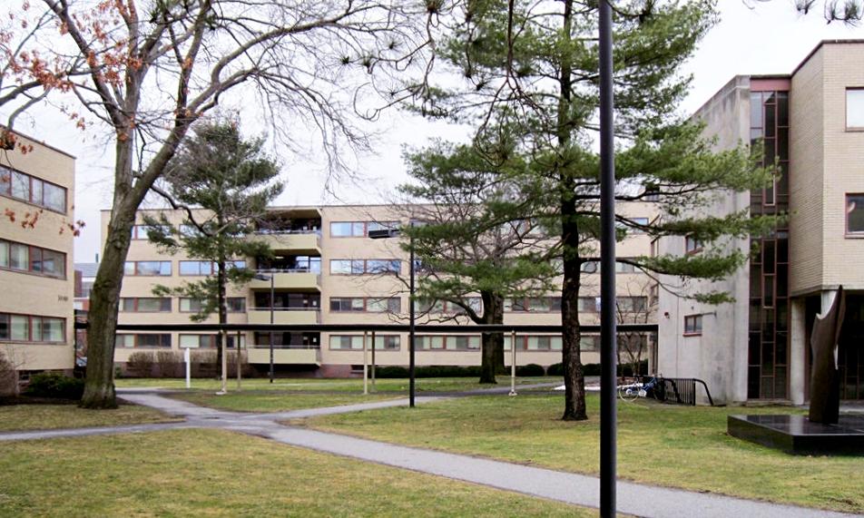 The courtyard of the Harvard Graduate Center with low-rise blocks and an abstract sculpture among the trees
