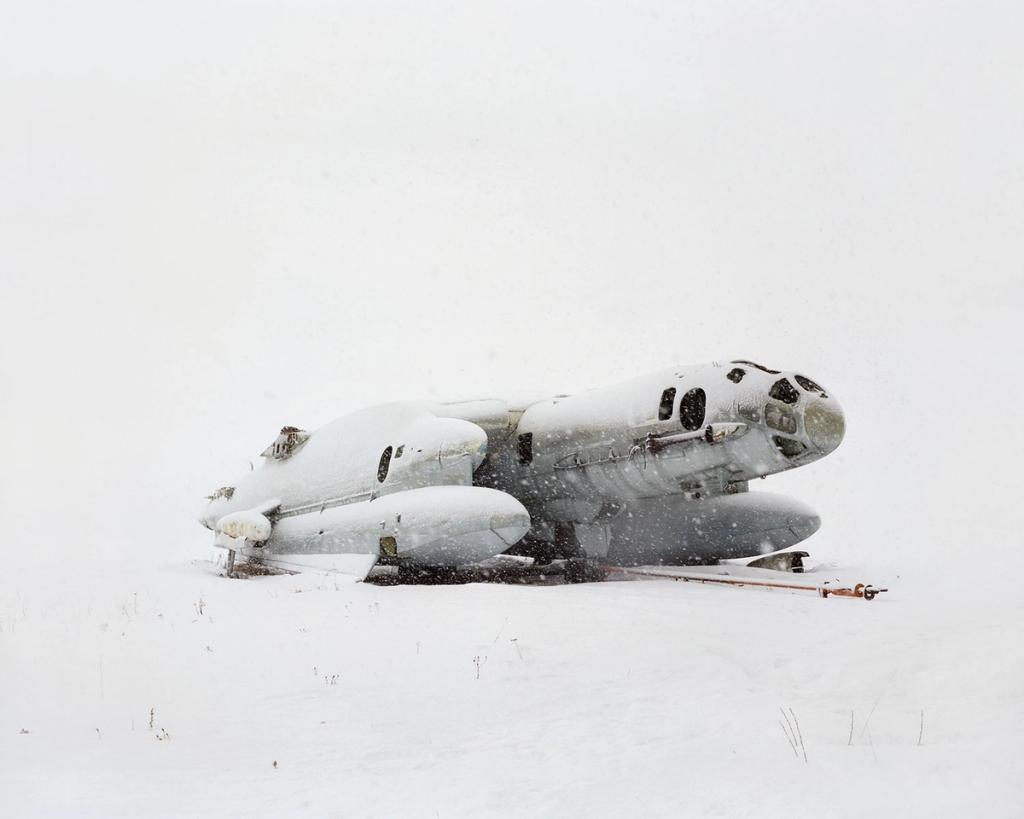 An abandoned ekranoplan with a rounded hull lying in a snow-covered field