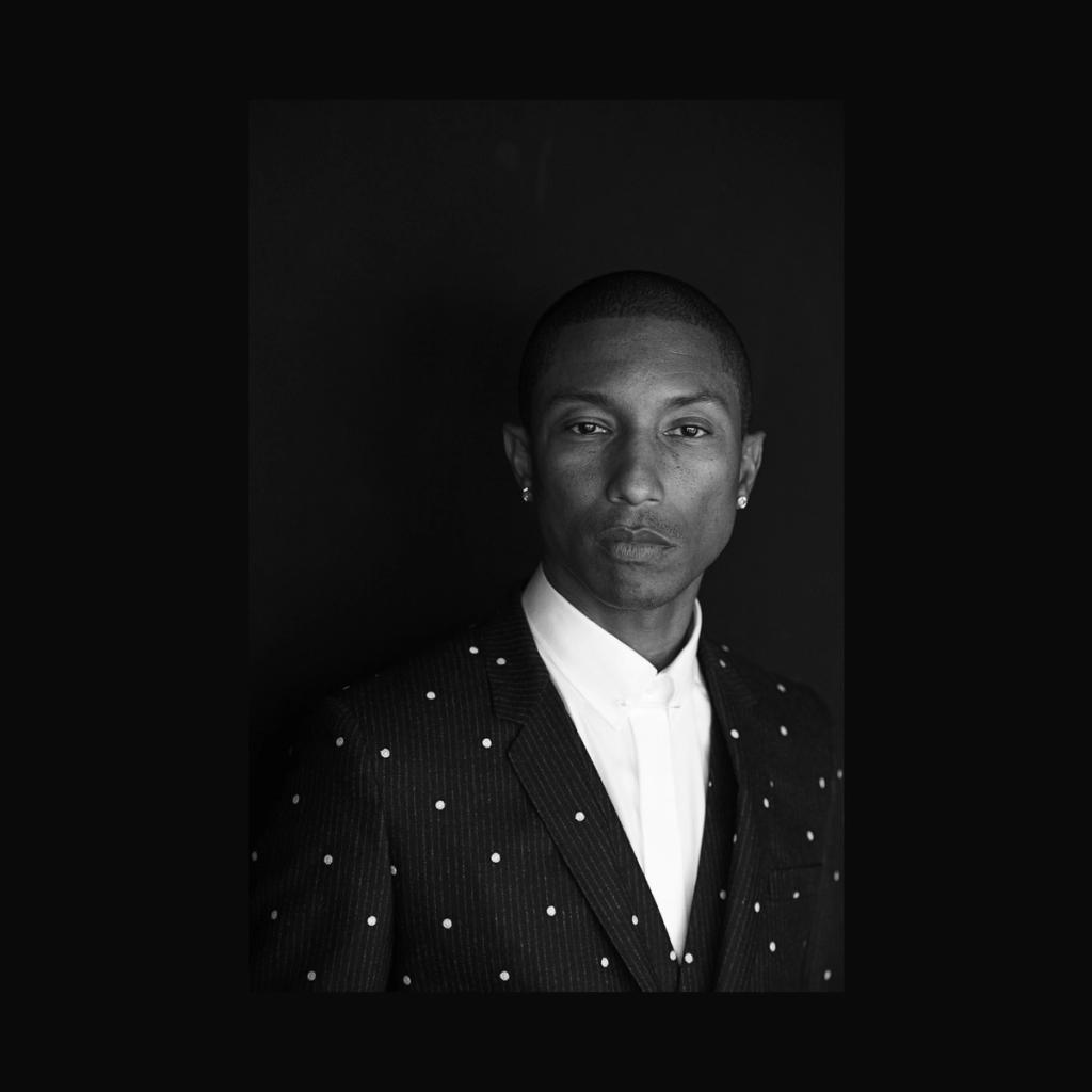 A black-and-white portrait of a man in a polka-dot jacket and white shirt against a dark background
