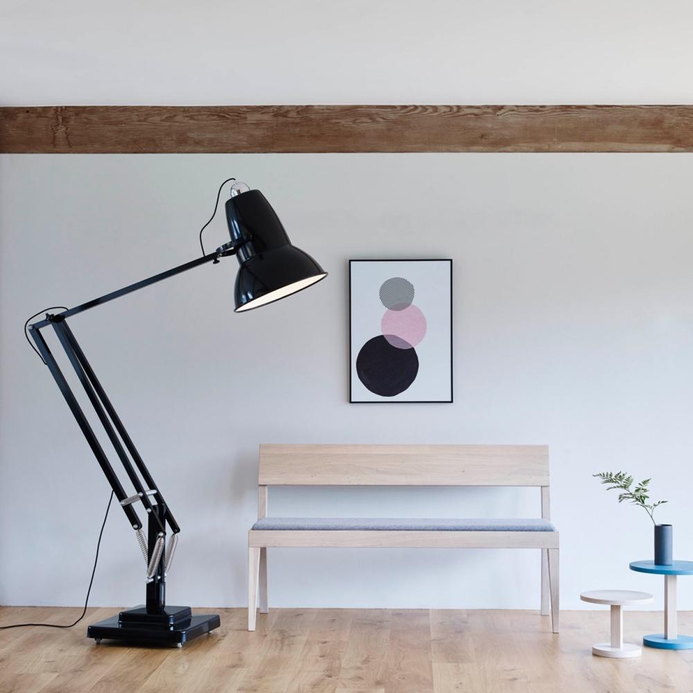 Гигантская чёрная напольная лампа Anglepoise рядом с деревянной скамьёй и абстрактным постером