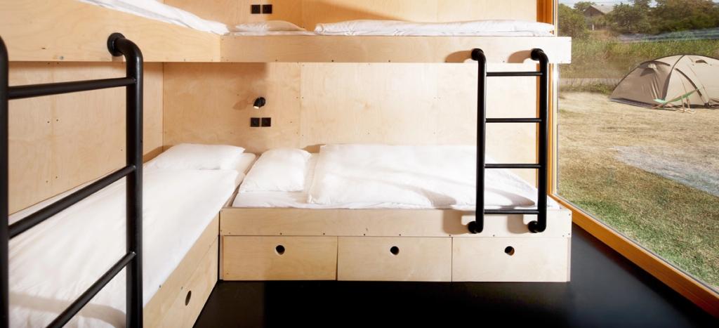 Двухъярусная кровать из фанеры в номере Containhotel с окном и видом на палатку