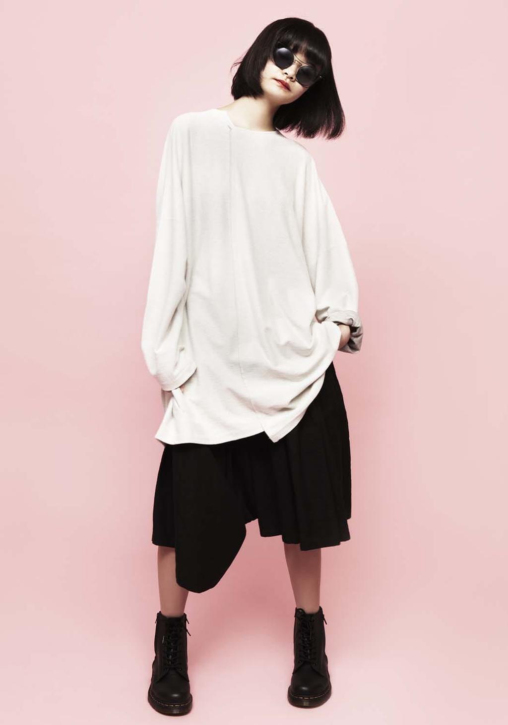 A model in an oversized white jumper and black short skirt, black boots