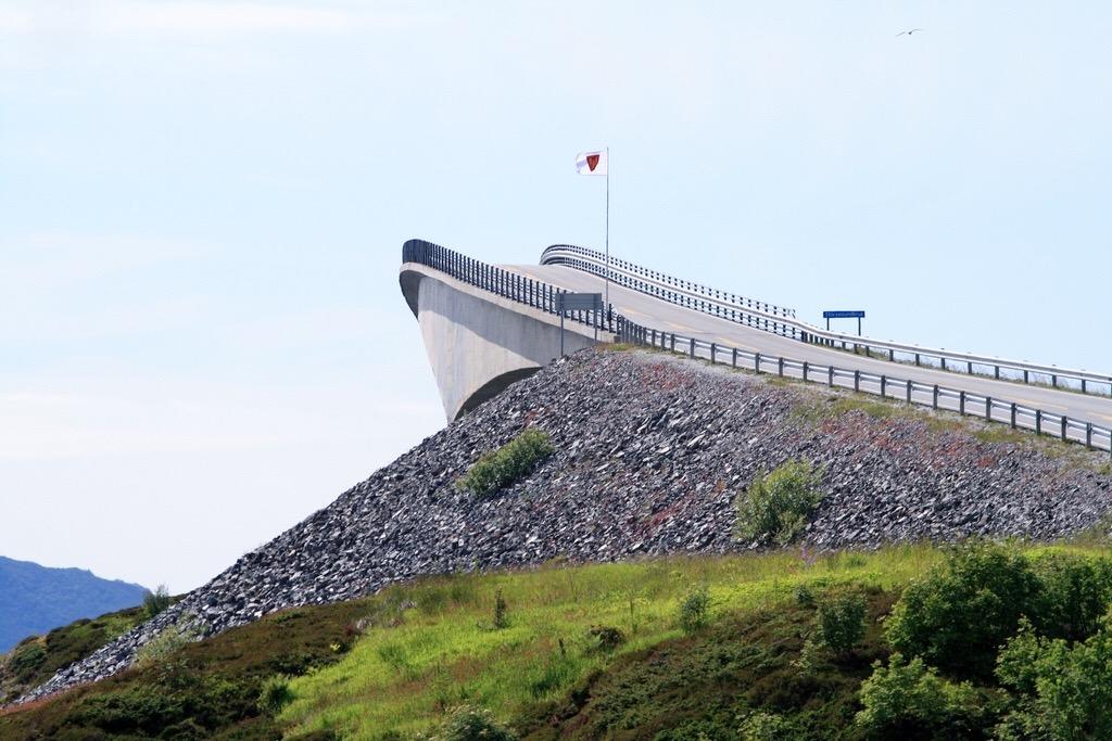 The sharp rise of the road on the Storseisundet Bridge, appearing to drop away into the sky, viewed from the shore