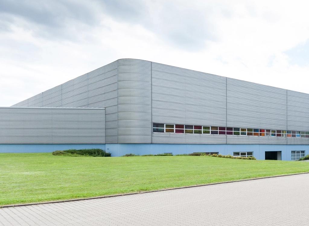 Завод Vitra Николаса Гримшоу с гофрированным алюминиевым фасадом и зелёной лужайкой